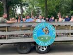 Group of people on wagon ride with campground logo on side of wagon at BUTTERFLY CAMPING RESORT - thumbnail