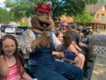 Bear mascot sitting with people on a wagon ride at BUTTERFLY CAMPING RESORT - thumbnail