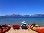 View larger image of Lady sitting in a chair next to a kayak with snowcapped mountains at TAHOE VALLEY CAMPGROUND image #6