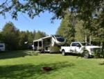 A white truck and a fifth wheel trailer in a site at COBOURG EAST CAMPGROUND - thumbnail