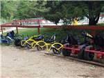 The pedal cars lined up by the fence at BADLANDS / WHITE RIVER KOA HOLIDAY - thumbnail