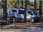 Class B in a gravel site surrounded by tall trees at CAMPER'S INN - thumbnail