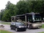 A car parked next to a motorhome in an RV site at BUCK CREEK RV PARK - thumbnail