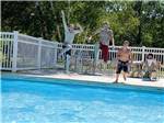 Three young boys jumping into the swimming pool at HOUGHTON LAKE TRAVEL PARK CAMPGROUND - thumbnail