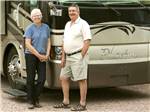 A couple standing in front of a motorhome at GOLDFIELD RV PARK - thumbnail