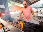 A man grilling food on the bbq pit at MUNDS PARK RV RESORT - thumbnail