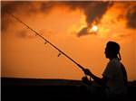 A silhouette of a man fishing at APACHE FAMILY CAMPGROUND & PIER - thumbnail
