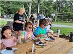 View larger image of Kids putting peanut butter on pine cones at COUNTRY ROADS CAMPGROUND image #4