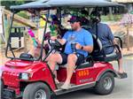 A man driving Mardi Gras revelers in a red golf cart - thumbnail