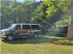 Campground van parked by a tree at Happy Holiday Campground - thumbnail