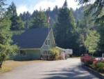 Campground entrance with building and trees in background at MYSTIC FOREST RV PARK - thumbnail