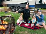 View larger image of People sitting around a fire pit with vintage trailers in the background at FLYING FLAGS RV RESORT  CAMPGROUND image #1