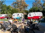 People sitting around a fire pit with vintage trailers in the background at FLYING FLAGS RV RESORT & CAMPGROUND - thumbnail