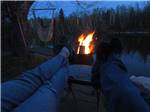 A couple laying in front of a fire at night at CAMPING PANORAMIC - thumbnail