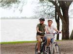 A couple riding bikes by the water at BRACKENRIDGE RECREATION COMPLEX - BRACKENRIDGE PARK & CAMPGROUND - thumbnail
