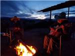 A man playing a guitar at a fire pit at BROWN'S TOWN CAMPGROUND - thumbnail