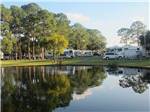 View larger image of Reflective water of lake with trailers in background at SOUTHERN PALMS RV RESORT image #4