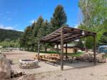 Picnic benches under a pavilion with a fire pit at SWAN VALLEY RV PARK - thumbnail