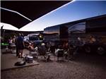 People hanging out around a motorhome at dusk at MCARTHUR'S TEMPLE VIEW RV RESORT - thumbnail