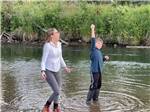 A girl and boy standing in the lake at RIVERSIDE RV AND CAMPER PARK - thumbnail