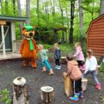 Yogi Bear in front of cabin at site Jellystone PA Wilds - thumbnail