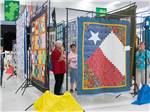 View larger image of Ladies looking at the quilts hanging at ALAMO ROSE RV RESORT image #8