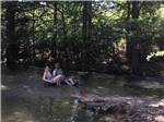 View larger image of A couple sitting in chairs in the river at BANDERA PIONEER RV RIVER RESORT image #6