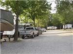 View larger image of RVs and trucks parked under leafy green trees at WANDERLUST RV PARK image #5