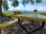 A yellow picnic bench and chairs at FALCON MEADOW RV CAMPGROUND - thumbnail
