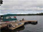 View larger image of A person sitting on a dock with boats at WOAHINK LAKE RV RESORT image #3