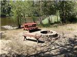 A fire pit and picnic table next to the river at BLACK RABBIT RV PARK - thumbnail
