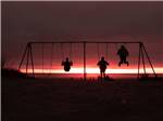 Kids on swing set against dusk sky at CIRCLE CREEK RV RESORT - thumbnail