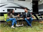 Couple lounging in their campsite at CIRCLE CREEK RV RESORT - thumbnail