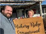 A couple holding up a mat with the campground name on it at HICKORY RIDGE CAMPGROUND - thumbnail