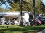 View larger image of A couple of trees in front of a trailer at THE SPRINGS RV RESORT image #5