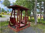 A red bench swing under trees at HAROLD W. DUFFETT SHRINERS RV PARK - thumbnail
