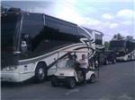 View larger image of RVs parked with people smiling in golf cart at OCALA SUN RV RESORT image #5