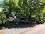 View larger image of Fifth wheels and a motorcycle under trees at PEACHTREE COVE RV PARK image #9