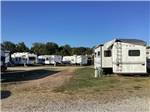 An empty gravel site next to a parked trailer at OVERLAND RV PARK - thumbnail