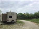 A gravel road by the RV sites at RUSTIC TRAILS RV PARK - thumbnail