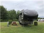 A fifth wheel trailer in a grassy RV site at CAMPING CHEZ JEAN, ENR.198004 - thumbnail