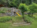 Playground in the grass at WHISPERING PINES CAMPGROUND & RV PARK - thumbnail