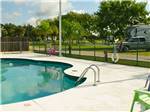 View larger image of Red plastic chair alongside community swimming pool at SONRISE PALMS RV PARK image #8