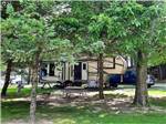 A fifth wheel trailer surrounded by trees at SHIPSHEWANA CAMPGROUND NORTH PARK & AMISH LOG CABIN LODGING - thumbnail