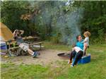 Family relaxing by fire pit at campsite at LAKE BYLLESBY CAMPGROUND - thumbnail