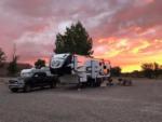 Truck and 5th wheel parked at a gravel site at sunset at Cadillac Ranch RV Park - thumbnail