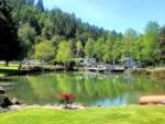 Large pond, flowers, trees, RVs, evergreen mountain in background at ON THE RIVER GOLF & RV RESORT - thumbnail