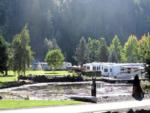 Large pond, RVs and an evergreen mountain backdrop at ON THE RIVER GOLF & RV RESORT - thumbnail