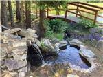 A small waterfall by a wooden bridge at MOUNTAIN MEADOW RV PARK & CABINS - thumbnail