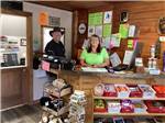 Two people standing behind the registration desk at MOUNTAIN MEADOW RV PARK & CABINS - thumbnail